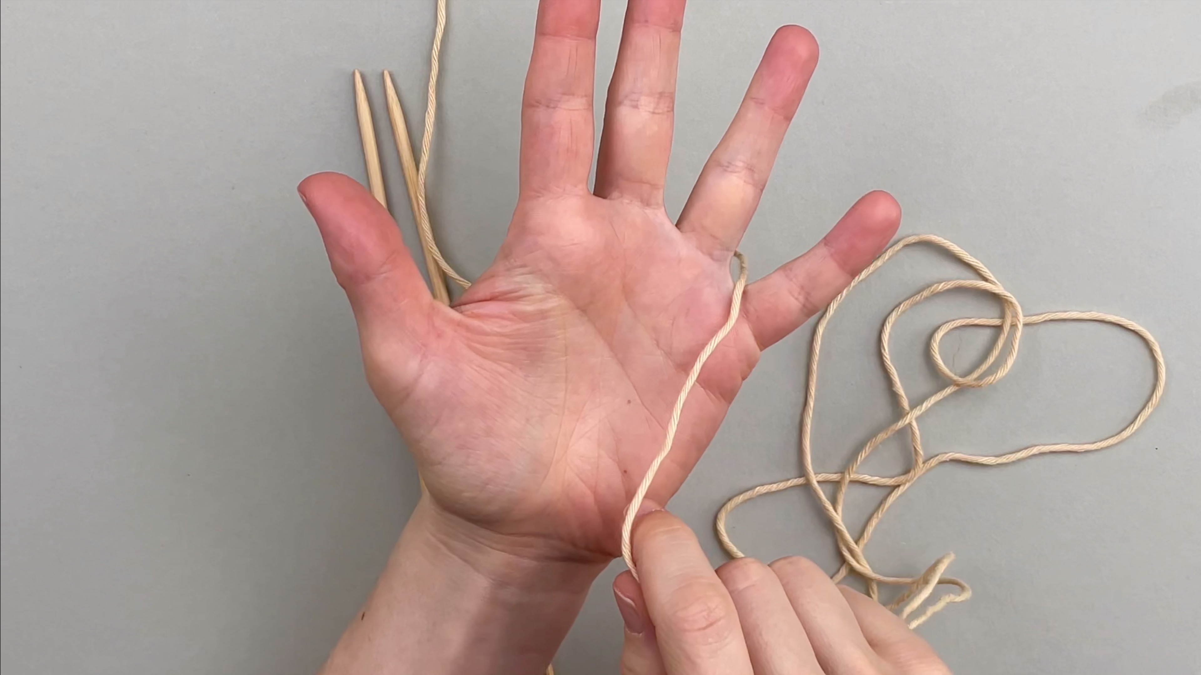 Das Garn wird zwischen den Ring- und den kleinen Finger gelegt