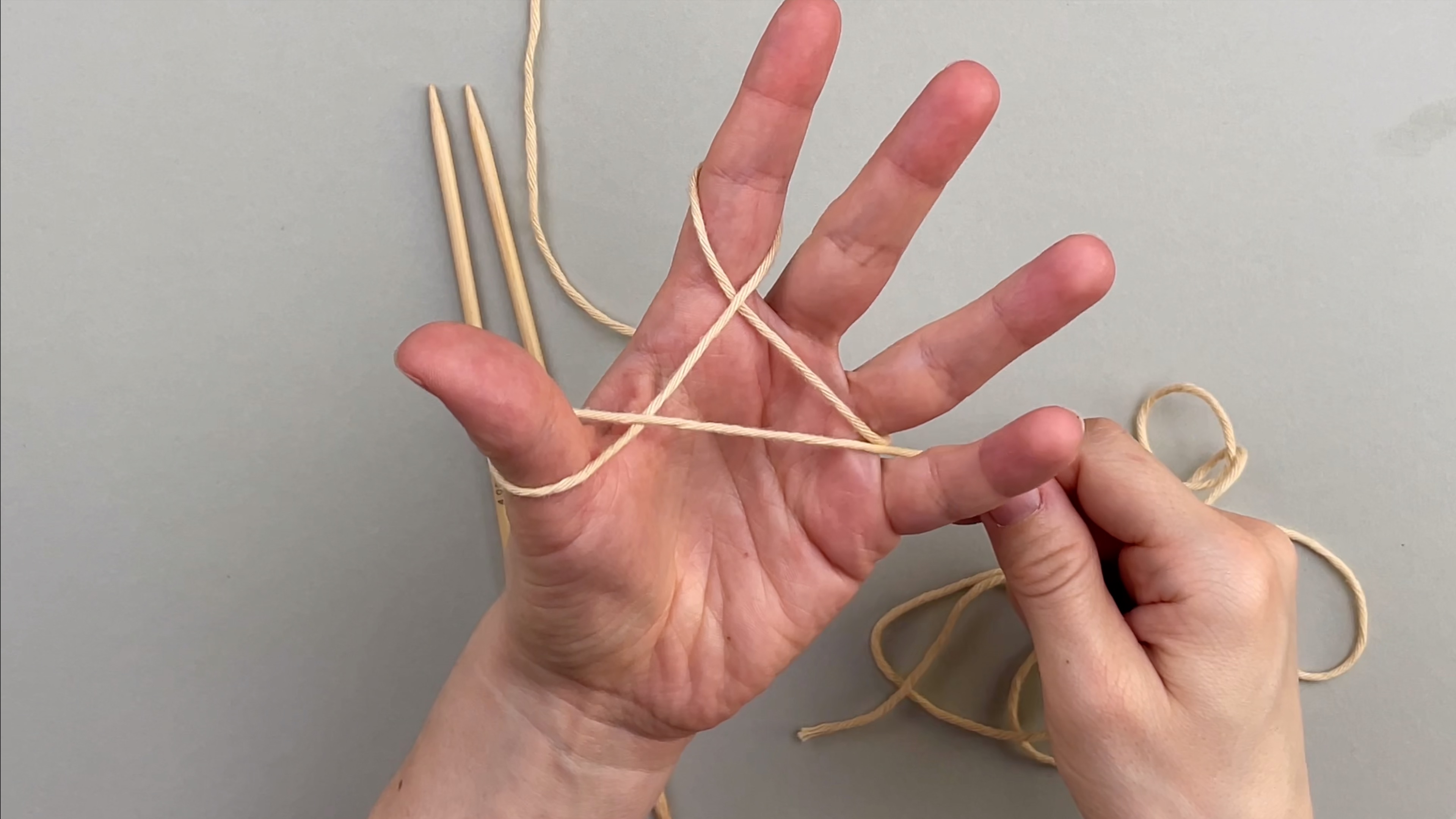 Den Arbeitsfaden um den Daumen wickeln